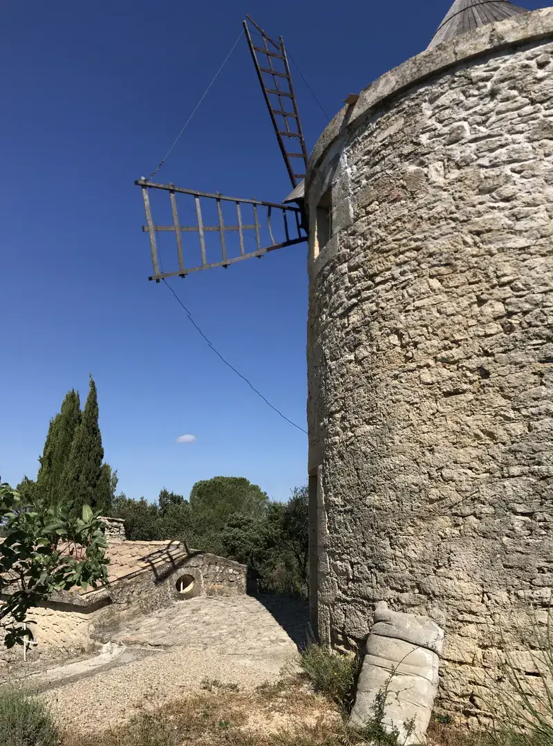 La tour de pierre et l'aile du moulin de Maître Cornille sous le ciel bleu du Gard